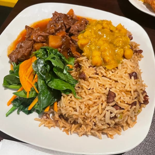 A Starving Vegan plate with vegan beef stew, yellow curry, rice and beans, and spinach.