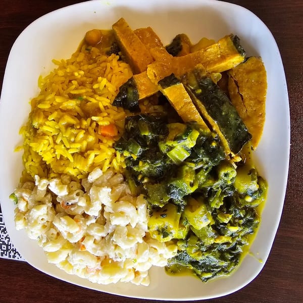 A Starving Vegan plate with yellow rice, macaroni salad, stewed greens, and sliced squash.