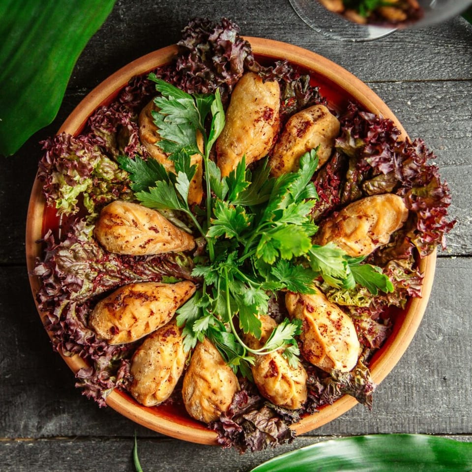 Vegan dumplings arranged on a bed of red and green lettuce, garnished with fresh parsley.